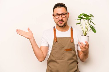 Beyaz arka planda bir bitki tutan İspanyol bahçıvan bir palmiye üzerinde fotokopi alanı ve belinde başka bir el tutan.