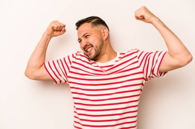 Beyaz arka planda izole edilmiş genç İspanyol bir adam zaferden sonra yumruk kaldırıyor, kazanan konsept..