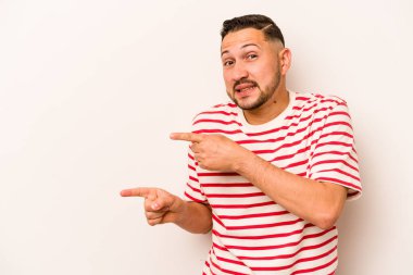 Beyaz arka planda izole edilmiş genç İspanyol adam işaret parmağıyla fotokopi alanını işaret ederek şok oldu..