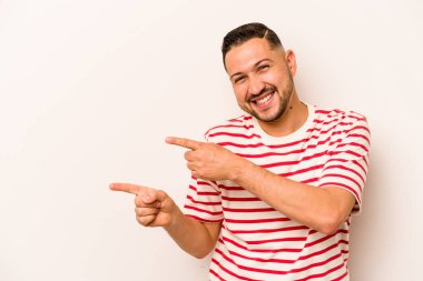 Beyaz arka planda izole edilmiş genç İspanyol adam işaret parmaklarıyla fotokopi alanını işaret ederek heyecan ve arzuyu ifade ediyor..