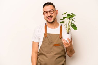 Beyaz arka planda saklanmış bir bitki tutan İspanyol bahçıvan mutlu, güler yüzlü ve neşeli.