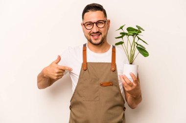 İspanyol bahçıvan elinde beyaz arka planda bir bitki tutuyor tişört fotokopisini elle gösteriyor, gururlu ve kendinden emin.