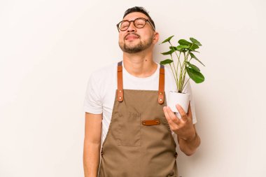 İspanyol bahçıvan beyaz arka planda bir bitki tutuyor. Amaçlarına ve amaçlarına ulaşma hayali kuruyor.