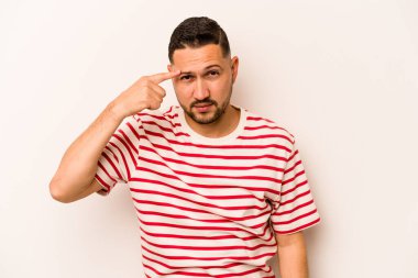 Beyaz arka planda izole edilmiş genç İspanyol bir adam şakağı parmağıyla işaret ediyor, düşünüyor ve bir göreve odaklanıyor..