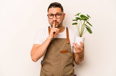 Beyaz arka planda bir bitki tutan İspanyol bahçıvan bir sır saklıyor ya da sessizlik istiyor..