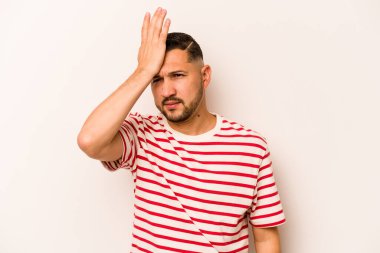 Beyaz arka planda izole edilmiş genç İspanyol bir adam bir şeyi unutuyor. Alnına avuç içi ile vuruyor ve gözlerini kapıyor..