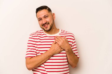 Beyaz arka planda izole edilmiş genç İspanyol bir adam, dost canlısı bir ifadeye sahip, avuçlarını göğsüne bastırıyor. Aşk konsepti.
