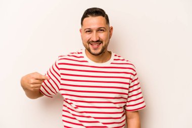 Beyaz arka planda izole edilmiş genç bir İspanyol gömlek fotokopi alanını elle işaret ediyor, gururlu ve kendinden emin.