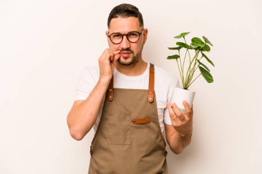 İspanyol bahçıvan, beyaz arka planda izole edilmiş bir bitki tutuyor. Parmakları dudaklarında sır saklıyor..