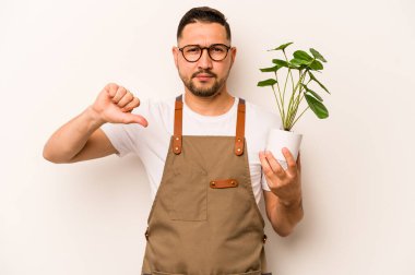 Beyaz arka planda izole edilmiş bir bitkiyi tutan İspanyol bahçıvan hoşlanmadığı bir jest gösteriyor. Anlaşmazlık konsepti.