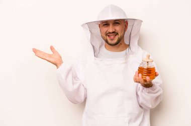 Beyaz arka planda bal tutan İspanyol arıcı avuçta fotokopi alanı ve belinde başka bir el tutan birini gösteriyor..