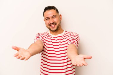 Beyaz arka planda izole edilmiş genç bir İspanyol hoş geldin ifadesi sergiliyor..