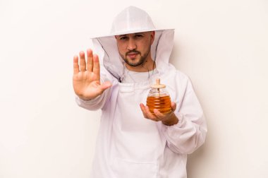 Beyaz arka planda izole edilmiş bal tutan İspanyol arıcı elini uzatmış, dur işareti göstererek seni engelliyor..