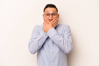 Beyaz arka planda izole edilmiş genç İspanyol adam elleriyle ağzını kapatırken şok oldu..