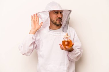 Beyaz arka planda izole edilmiş bal tutan İspanyol arıcı bir dedikoduyu dinlemeye çalışıyor..