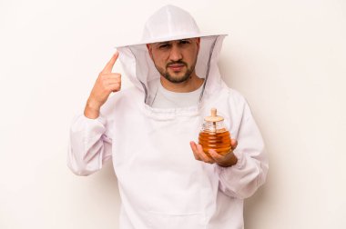 Beyaz arka planda izole edilmiş bal tutan İspanyol arı yetiştiricisi işaret parmağıyla yaptığı hayal kırıklığını gösteriyor..