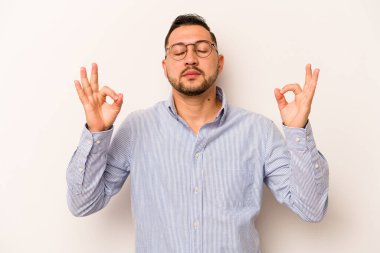 Beyaz arka planda izole olmuş genç İspanyol adam sıkı çalışma gününden sonra rahatlıyor, yoga yapıyor..