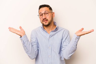 Beyaz arka planda izole edilmiş genç İspanyol bir adam. Kafası karışmış ve omuz silkiyor. Kopya alanını tutmak için..