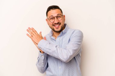 Beyaz arka planda izole edilmiş genç İspanyol adam enerjik ve rahat hissediyor, ellerini ovuşturuyor..