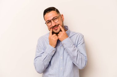 Latin kökenli genç bir adam beyaz arka planda iki seçenek arasında kuşkulanıyor..