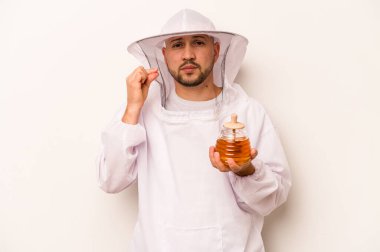 Beyaz arka planda bal tutan İspanyol arıcı. Parmakları dudaklarında sır saklıyor..