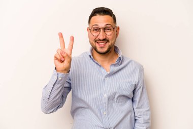 Beyaz arka planda izole edilmiş genç İspanyol adam iki numarayı parmaklarıyla gösteriyor..