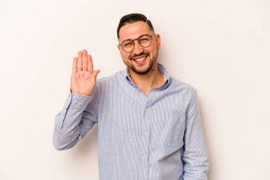 Beyaz arka planda izole edilmiş genç İspanyol adam gülümseyerek beş numarayı parmaklarıyla gösteriyor..