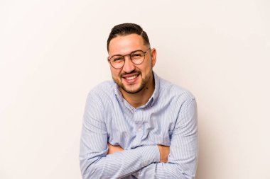 Beyaz arka planda yaşayan genç İspanyol adam gülüyor ve eğleniyor..