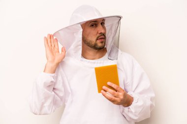 Beyaz arka planda izole edilmiş bal tutan İspanyol arıcı bir dedikoduyu dinlemeye çalışıyor..