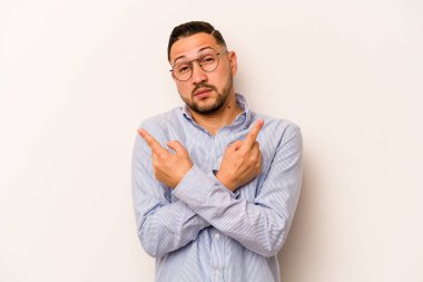 Beyaz arka plan noktalarında izole edilmiş genç İspanyol adam iki seçenek arasında seçim yapmaya çalışıyor..