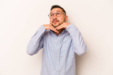 Beyaz arka planda izole edilmiş genç İspanyol adam ellerini çenesinin altında tutuyor ve mutlu bir şekilde yan tarafa bakıyor..