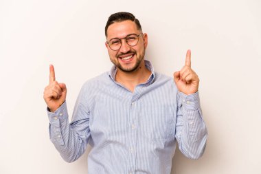 Beyaz arka planda izole edilmiş genç İspanyol bir adam iki parmağı da boş bir alan gösteriyor..