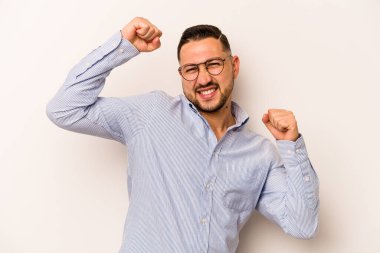 Beyaz arka planda izole edilmiş genç bir İspanyol özel bir günü kutluyor, atlıyor ve enerjiyle kollarını kaldırıyor..