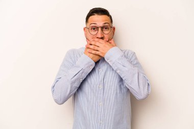 Beyaz arka planda izole edilmiş genç İspanyol adam elleri endişeli bir şekilde ağzı örtüyor..