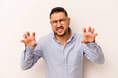 Beyaz arka planda izole edilmiş genç İspanyol bir adam pençelerini bir kediyi taklit ederken gösteriyor, agresif bir hareket..