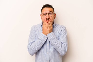 Beyaz arka planda izole edilmiş genç İspanyol adam şok olmuş, ağzı ellerle kaplanmış, yeni bir şey keşfetmeye hevesli..