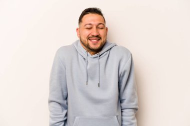 Beyaz arka planda izole edilmiş genç İspanyol adam gülüyor ve gözlerini kapıyor, rahatlamış ve mutlu hissediyor..