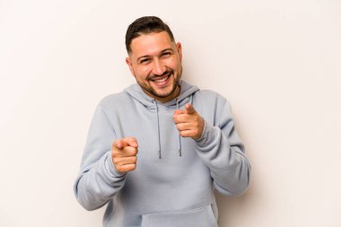 Beyaz arka planda izole edilmiş genç İspanyol adam parmaklarıyla ön tarafı işaret ediyor..