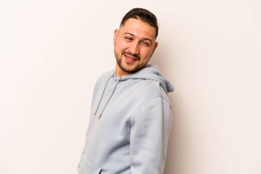 Beyaz arka planda soyutlanmış genç İspanyol adam gülümseyen, neşeli ve keyifli bir kenara bakıyor..