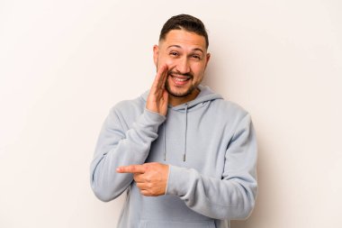 Latin kökenli genç bir adam beyaz arka planda izole edilmiş. Dedikodu yapıyor, bir şeyleri bildiriyor..