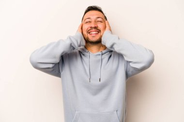Beyaz arka planda izole edilmiş genç İspanyol adam ellerini başının üstünde tutarak neşeyle gülüyor. Mutluluk kavramı.