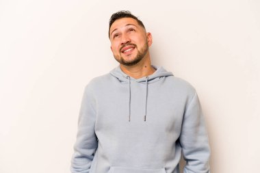 Beyaz arka planda izole edilmiş genç bir İspanyol. Rahatlamış ve mutlu bir şekilde gülüyor. Boynunda dişler var..