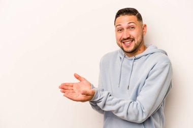 Beyaz arka planda izole edilmiş genç İspanyol bir adam avucunun içinde bir kopyasını tutuyor..