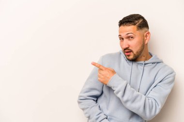 Latin kökenli genç adam beyaz arka planda izole edilmiş, başparmak uzakta, gülüyor ve kaygısız..