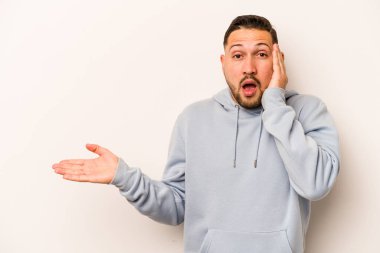 Beyaz arka planda izole edilmiş genç İspanyol adam, avuç içinde kopya alanı tutmaktan etkilenmiş..