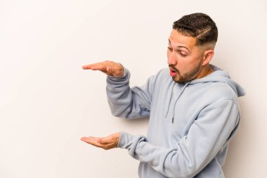 Beyaz arka planda izole edilmiş genç İspanyol adam elleri arasında bir kopya alanı tutarken şok ve hayrete düştü..