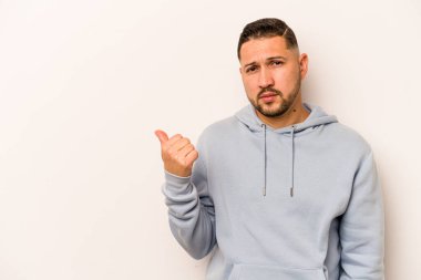 Beyaz arka planda izole edilmiş genç İspanyol adam işaret parmağıyla fotokopi alanını işaret ederek şok oldu..