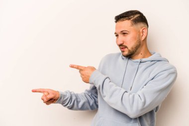 Beyaz arka planda izole edilmiş genç İspanyol adam işaret parmaklarıyla fotokopi alanını işaret ederek heyecan ve arzuyu ifade ediyor..