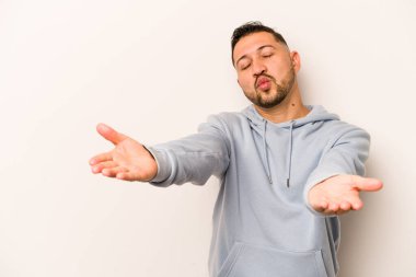 Beyaz arka planda izole edilmiş, dudakları kıvrılmış ve hava öpücüğü yollamak için avuç içi tutan İspanyol bir adam..