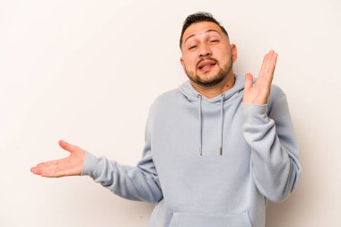 Beyaz arka planda izole edilmiş genç İspanyol bir adam avuç içinde fotokopi alanı tutuyor, el üstünde tutuyor. Şaşırmış ve mutlu..